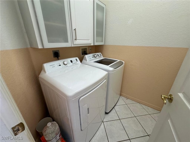 laundry room featuring washer and dryer, cabinets, and light tile patterned flooring