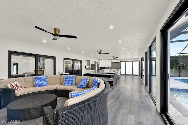 living room featuring ceiling fan, a textured ceiling, and light hardwood / wood-style flooring