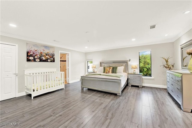 bedroom featuring connected bathroom, light hardwood / wood-style flooring, and crown molding