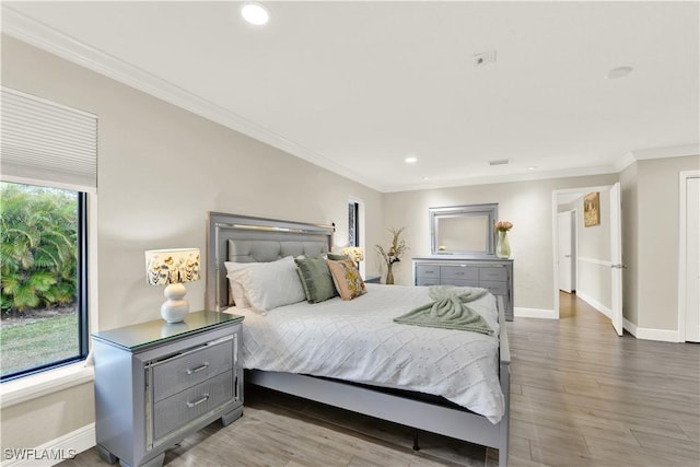 bedroom featuring light wood-type flooring, multiple windows, and crown molding