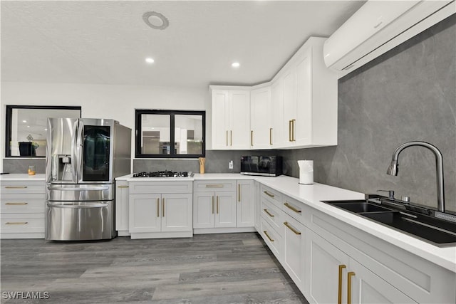 kitchen with white cabinetry, sink, appliances with stainless steel finishes, and a wall mounted AC