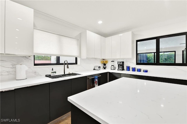 kitchen featuring dishwasher, tasteful backsplash, white cabinetry, and sink