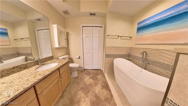 bathroom featuring a washtub, vanity, and toilet