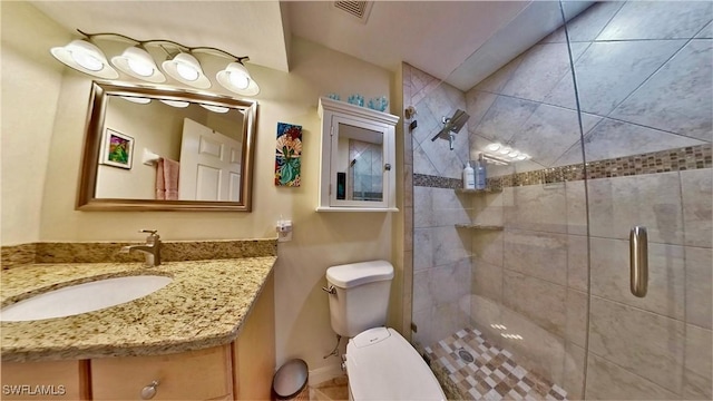 bathroom with vanity, toilet, and a shower with door