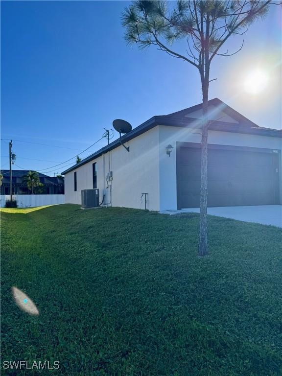 view of property exterior with a garage, cooling unit, and a lawn