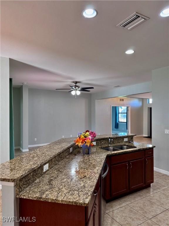 kitchen featuring ceiling fan, sink, stone countertops, dishwasher, and light tile patterned flooring