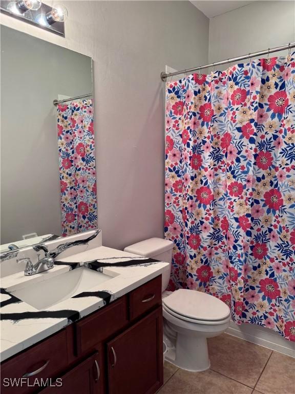 bathroom with curtained shower, tile patterned flooring, vanity, and toilet