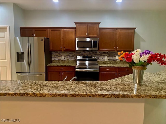 kitchen with light stone countertops, backsplash, and appliances with stainless steel finishes