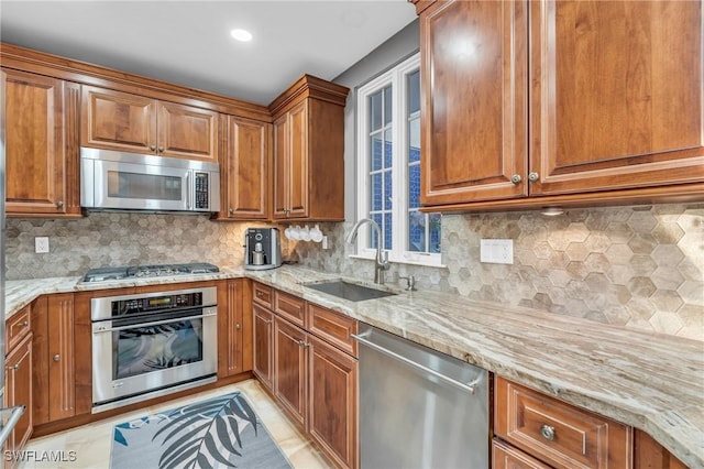 kitchen featuring appliances with stainless steel finishes, backsplash, light stone counters, and sink