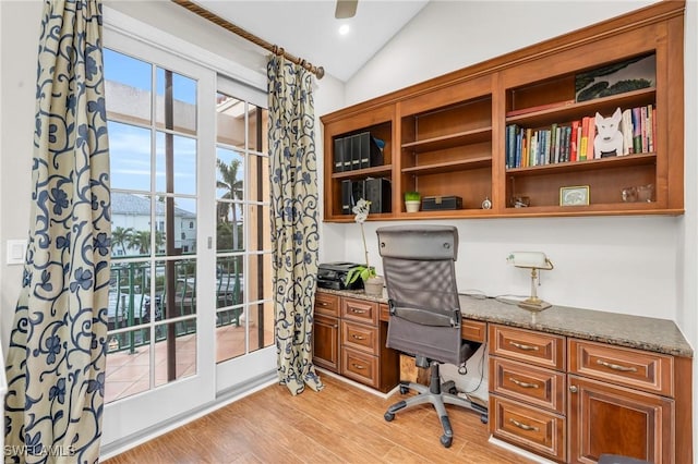 home office with built in desk, light hardwood / wood-style floors, and vaulted ceiling