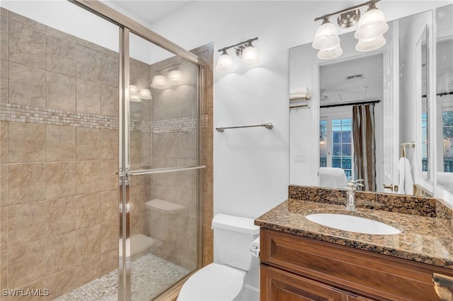 bathroom featuring vanity, toilet, and a shower with shower door