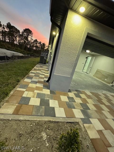 property exterior at dusk featuring cooling unit and a patio area