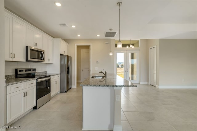 kitchen featuring sink, an island with sink, appliances with stainless steel finishes, decorative light fixtures, and white cabinetry