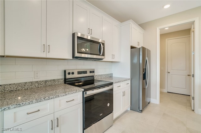 kitchen with white cabinetry, light stone countertops, tasteful backsplash, light tile patterned floors, and appliances with stainless steel finishes