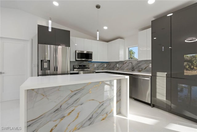 kitchen with decorative backsplash, light stone counters, stainless steel appliances, vaulted ceiling, and hanging light fixtures