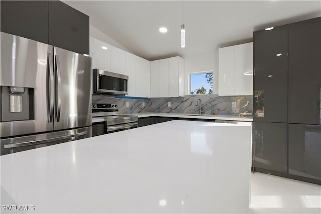 kitchen featuring white cabinets, decorative light fixtures, backsplash, and stainless steel appliances