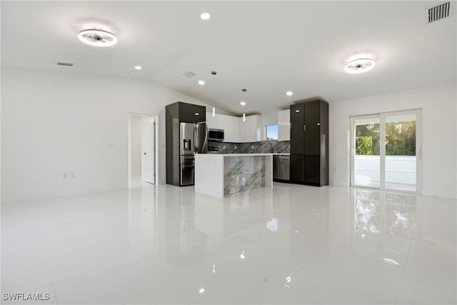 kitchen with stainless steel appliances, vaulted ceiling, a kitchen island, and light tile patterned flooring