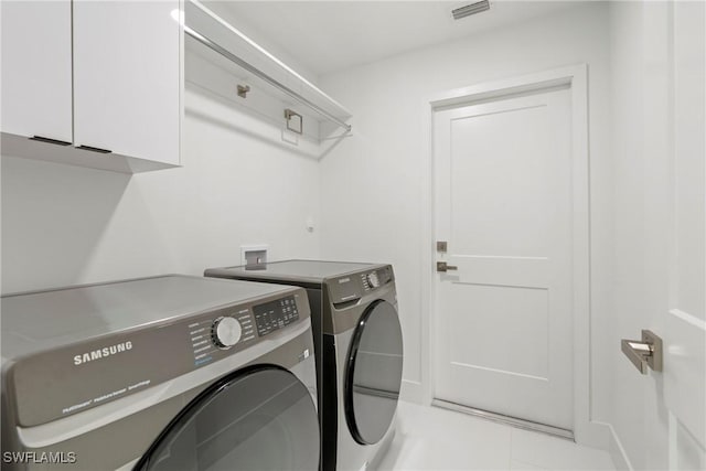 washroom featuring light tile patterned flooring, cabinets, and washing machine and dryer