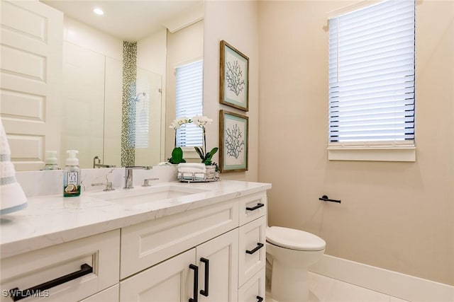 bathroom featuring vanity, toilet, plenty of natural light, and a shower with shower door