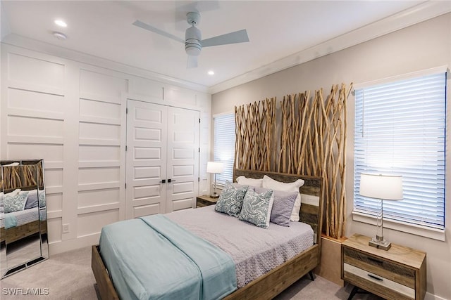 bedroom with crown molding, ceiling fan, a closet, and light colored carpet