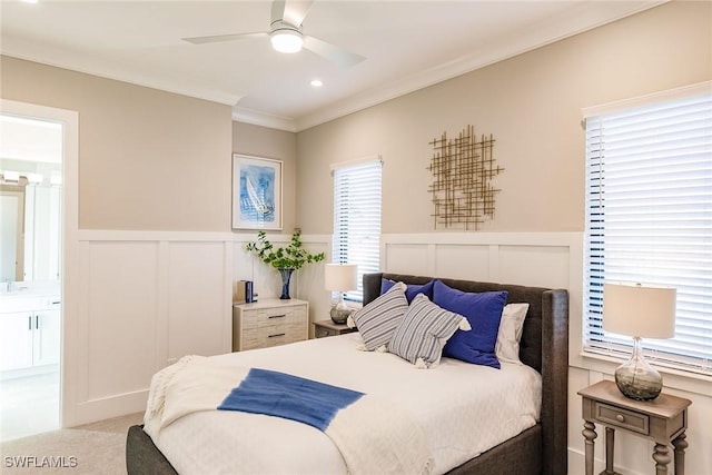 carpeted bedroom with connected bathroom, ceiling fan, multiple windows, and ornamental molding