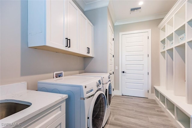 clothes washing area with cabinets, crown molding, sink, separate washer and dryer, and light hardwood / wood-style flooring