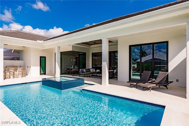 view of pool featuring exterior bar, an in ground hot tub, a patio area, and exterior kitchen