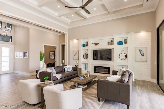 living room with beam ceiling, coffered ceiling, a high ceiling, light hardwood / wood-style flooring, and ceiling fan with notable chandelier