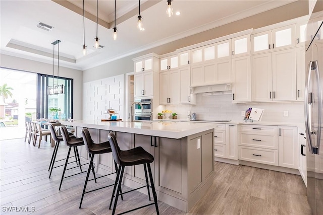 kitchen featuring a kitchen island, white cabinetry, hanging light fixtures, and a tray ceiling