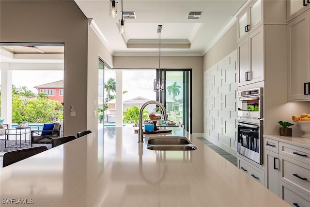 kitchen featuring hanging light fixtures, white cabinetry, sink, and stainless steel double oven