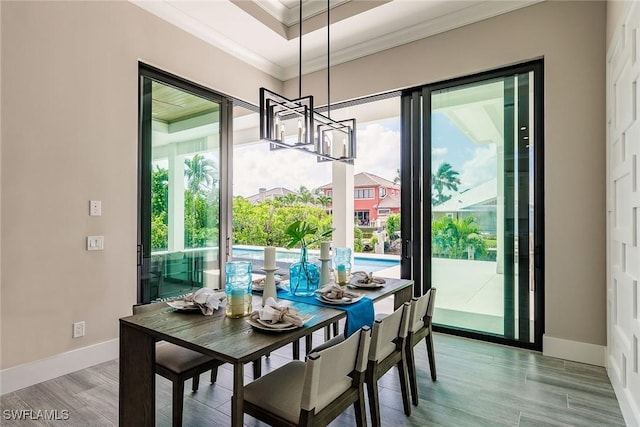 dining area featuring plenty of natural light, an inviting chandelier, ornamental molding, and light hardwood / wood-style flooring