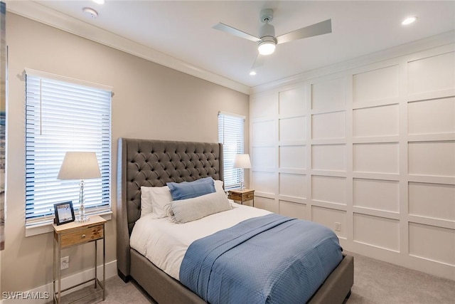 carpeted bedroom with multiple windows, ceiling fan, and ornamental molding