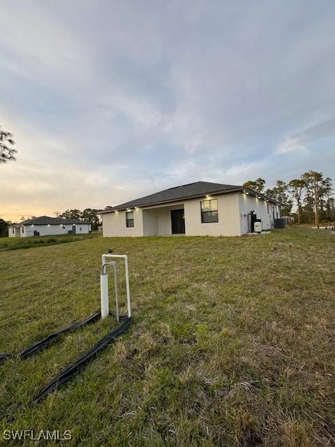 property exterior at dusk featuring a yard