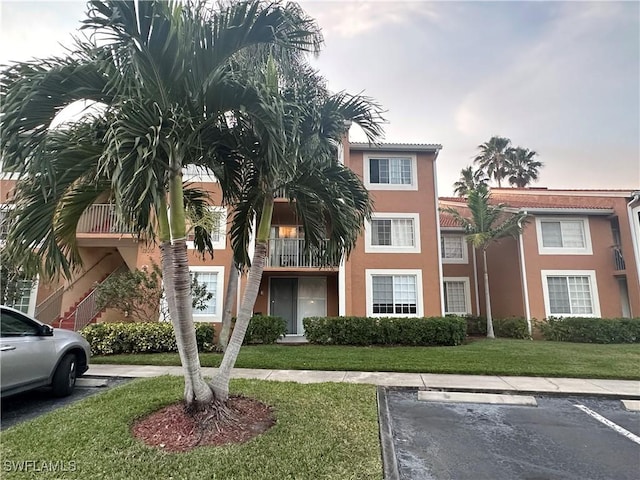 1275 Wildwood Lakes Blvd Unit 105, Naples, FL 34104 - view of front of property featuring a front lawn, uncovered parking, and stucco siding