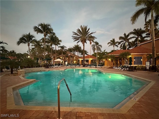 pool at dusk featuring a patio area