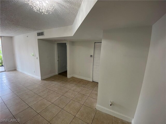 1275 Wildwood Lakes Blvd Unit 105, Naples, FL 34104 - empty room featuring light tile patterned flooring, baseboards, a textured ceiling, and visible vents