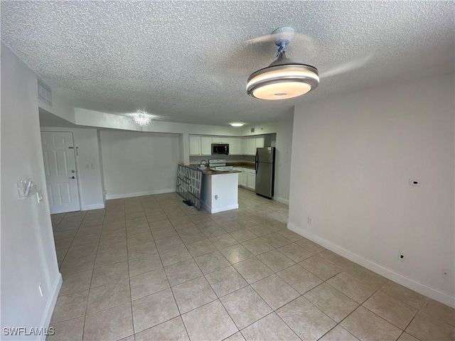 1275 Wildwood Lakes Blvd Unit 105, Naples, FL 34104 - kitchen featuring freestanding refrigerator, open floor plan, stove, stainless steel microwave, and visible vents