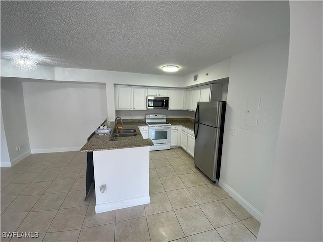1275 Wildwood Lakes Blvd Unit 105, Naples, FL 34104 - kitchen featuring a sink, appliances with stainless steel finishes, a peninsula, light tile patterned floors, and white cabinets