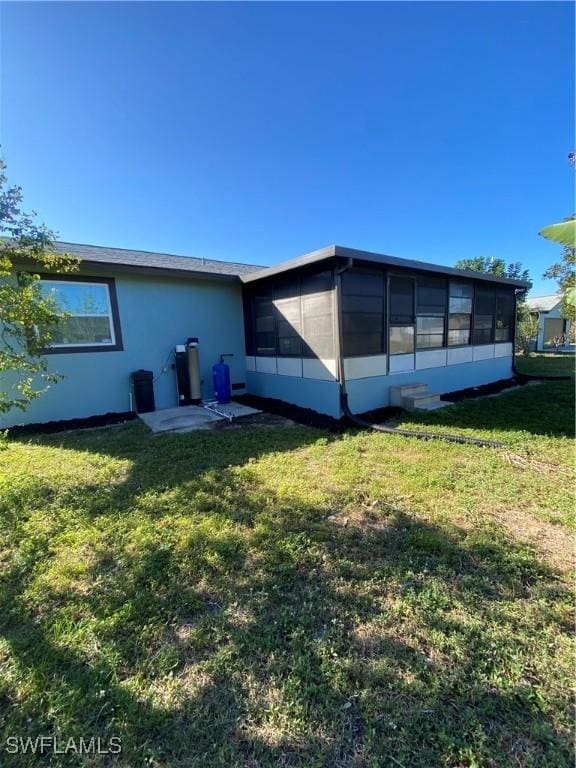 back of property with a sunroom and a yard