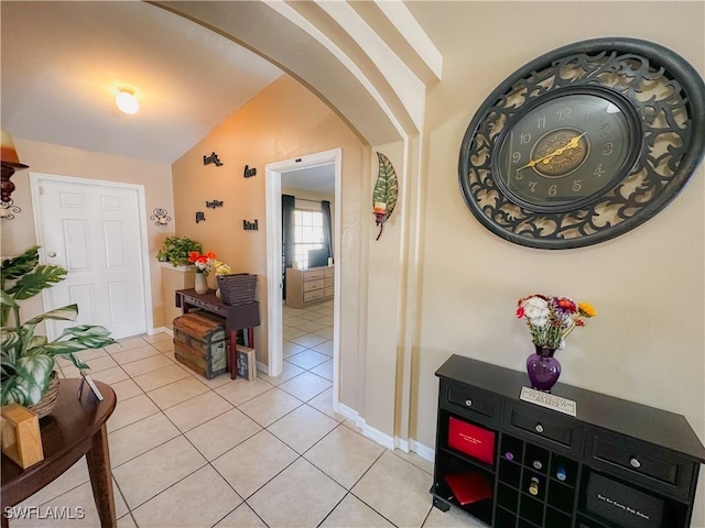 hall with vaulted ceiling and light tile patterned floors