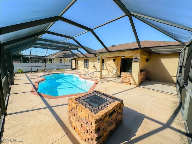 view of pool with an outdoor fire pit, glass enclosure, and a patio