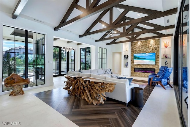 living room with beam ceiling, a stone fireplace, high vaulted ceiling, and french doors