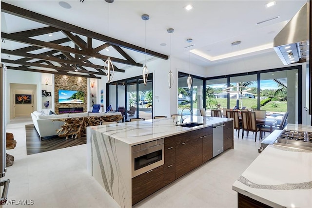 kitchen featuring a large island, sink, hanging light fixtures, stainless steel appliances, and a fireplace