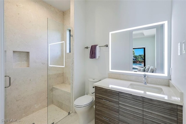 bathroom featuring a shower with door, vanity, and toilet