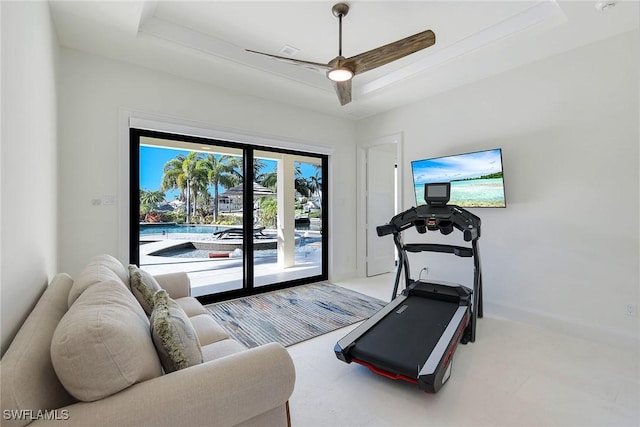 exercise room featuring a raised ceiling and ceiling fan