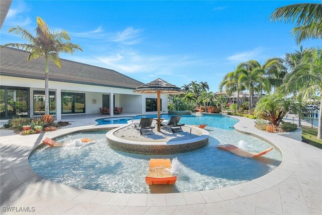 view of swimming pool with pool water feature and a hot tub