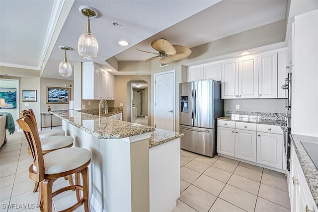 kitchen featuring stainless steel refrigerator with ice dispenser, white cabinetry, ceiling fan, and pendant lighting