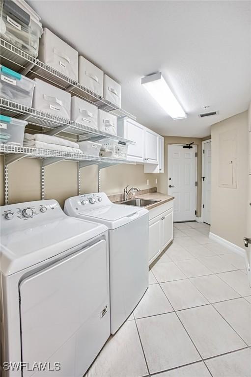 washroom with cabinets, sink, light tile patterned floors, and washer and dryer