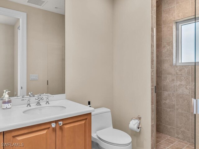 bathroom featuring tiled shower, vanity, and toilet