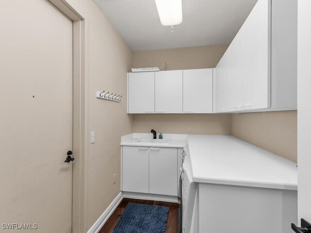 laundry area featuring cabinets, dark hardwood / wood-style flooring, washer / clothes dryer, and sink